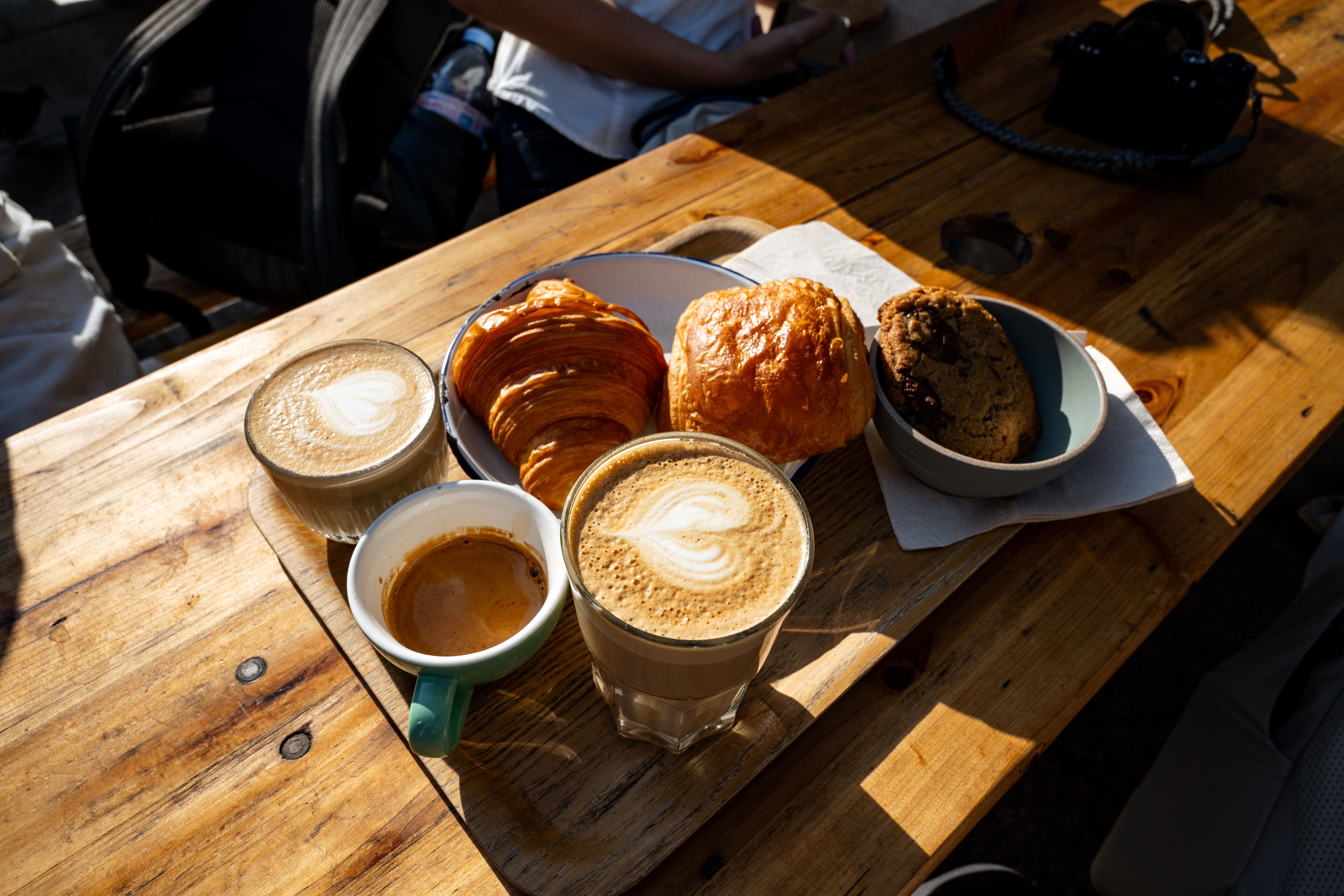 A warm sunlit breakfast scene with croissants, coffee, and pastries outdoors in Paris.