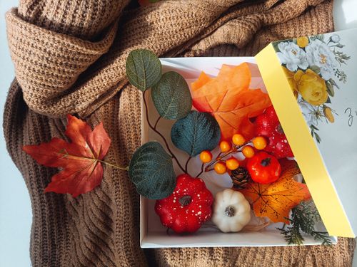 Free Autumn-themed gift box with decorative pumpkins, leaves, and warm knit fabric. Stock Photo
