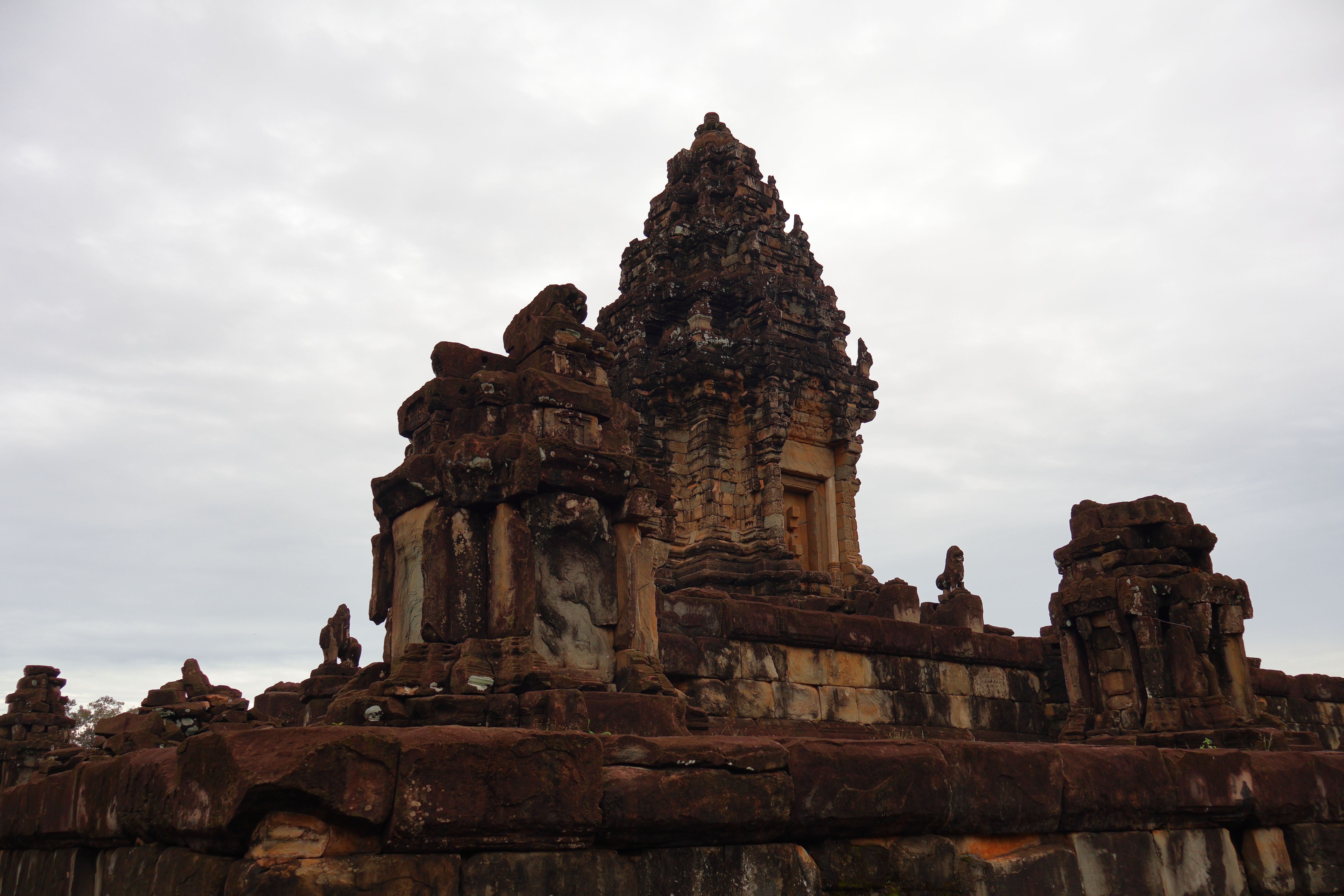 Detailed view of ancient stone temple ruins under a cloudy sky, showcasing intricate carvings.