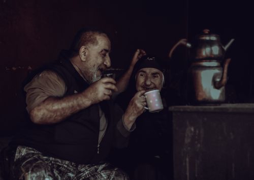 Free Two elderly men enjoying a warm drink together, sharing a joyful moment indoors. Stock Photo