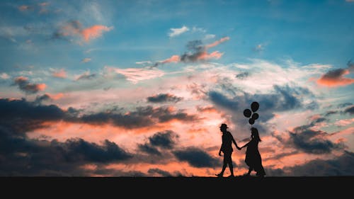 Silhouette of Man and Woman Holding Hands during Sunset