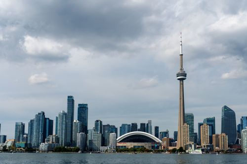 Free Stunning view of Toronto's skyline with the iconic CN Tower and Rogers Centre under a cloudy sky. Stock Photo