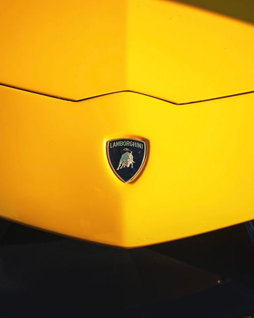 Free Detailed view of a Lamborghini emblem on a vibrant yellow sports car. Stock Photo