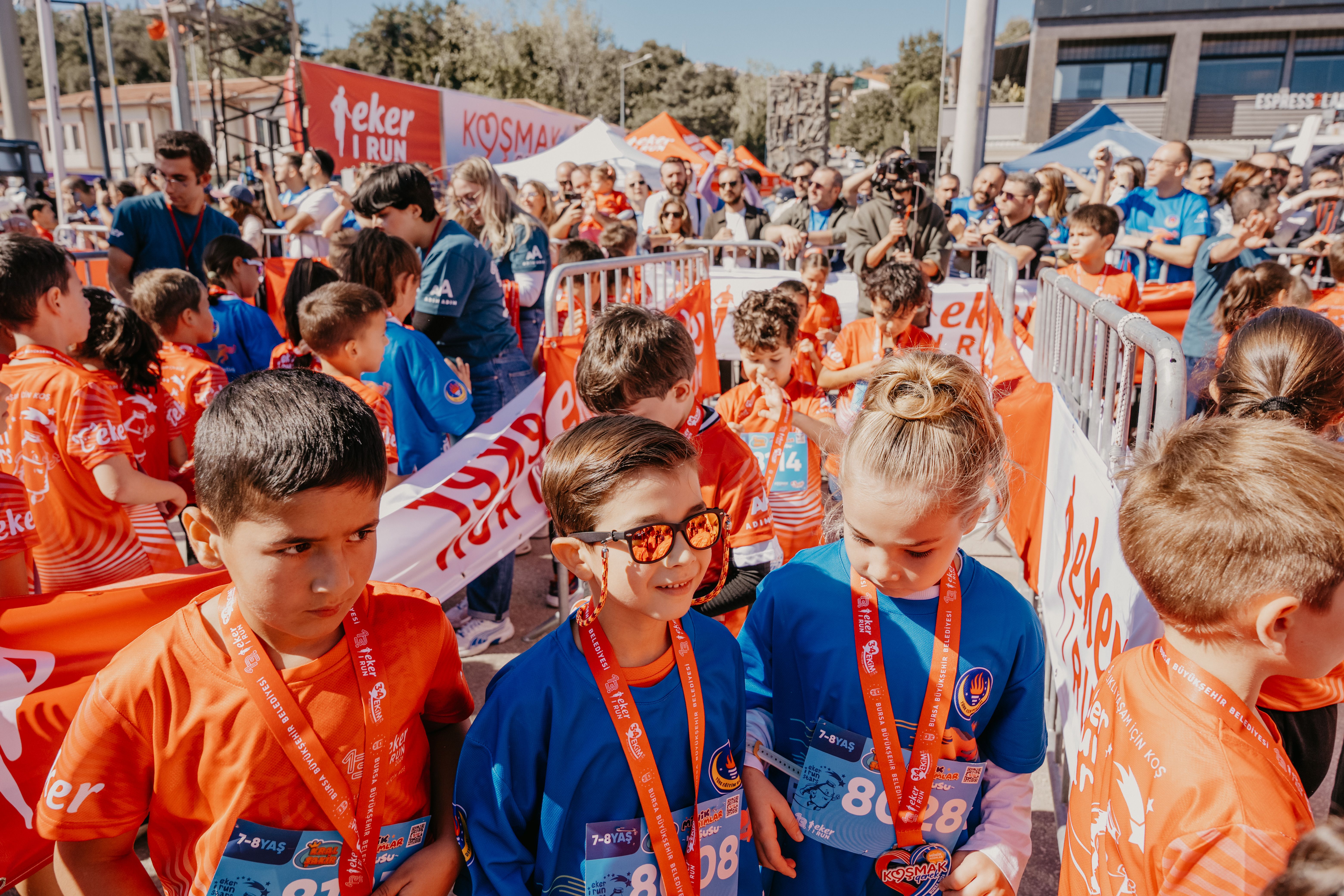 Group of children at an outdoor fun run event, wearing race bibs and medals, enjoying a sunny day. - Photo by İslam Abruev on Pexels