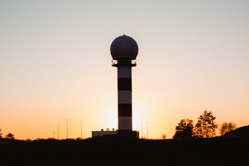 Free A radar tower silhouetted against a vibrant sunset with clear skies. Stock Photo