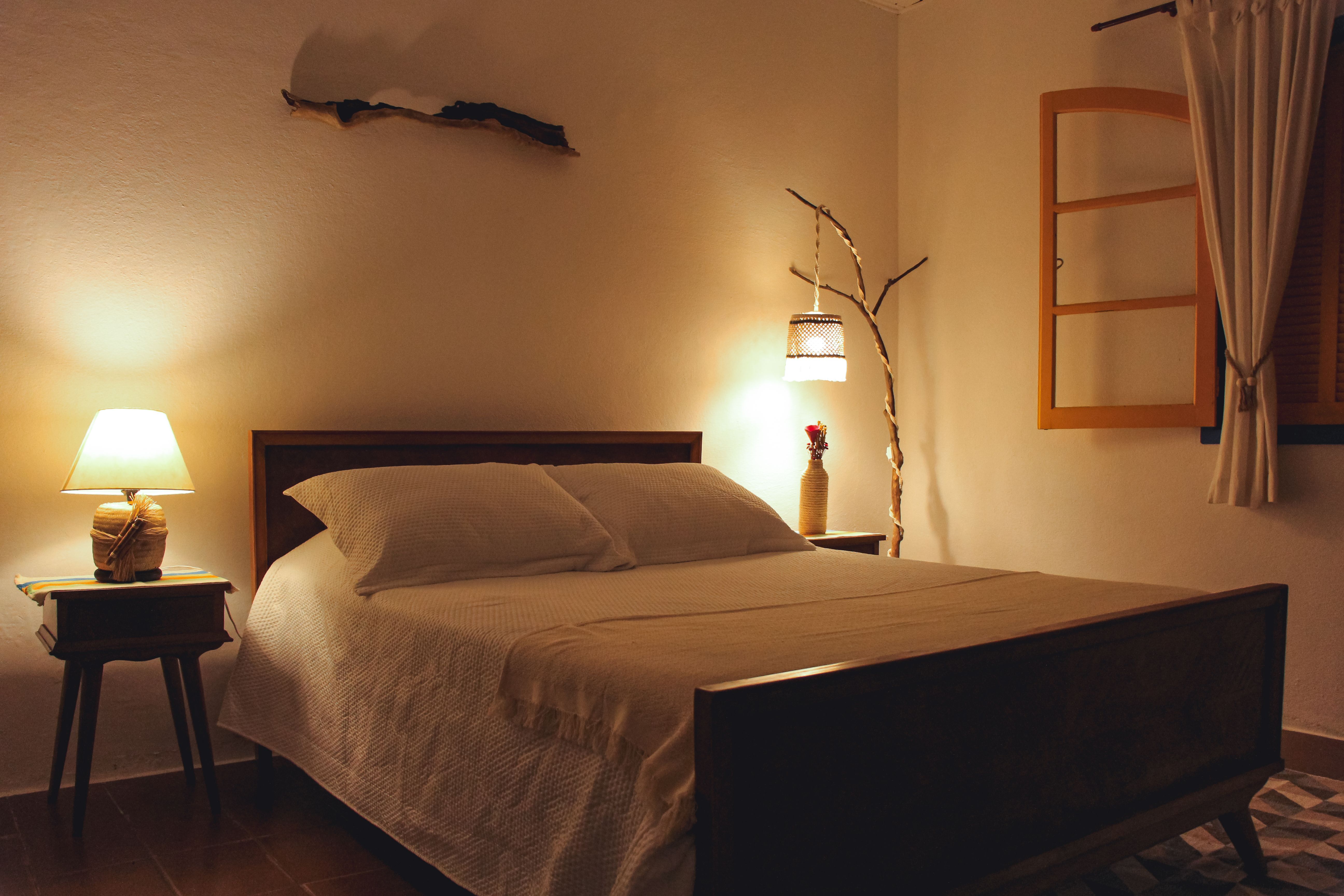 Fotomural Habitación acogedora con luz cálida, cama de madera y decoración rústica.