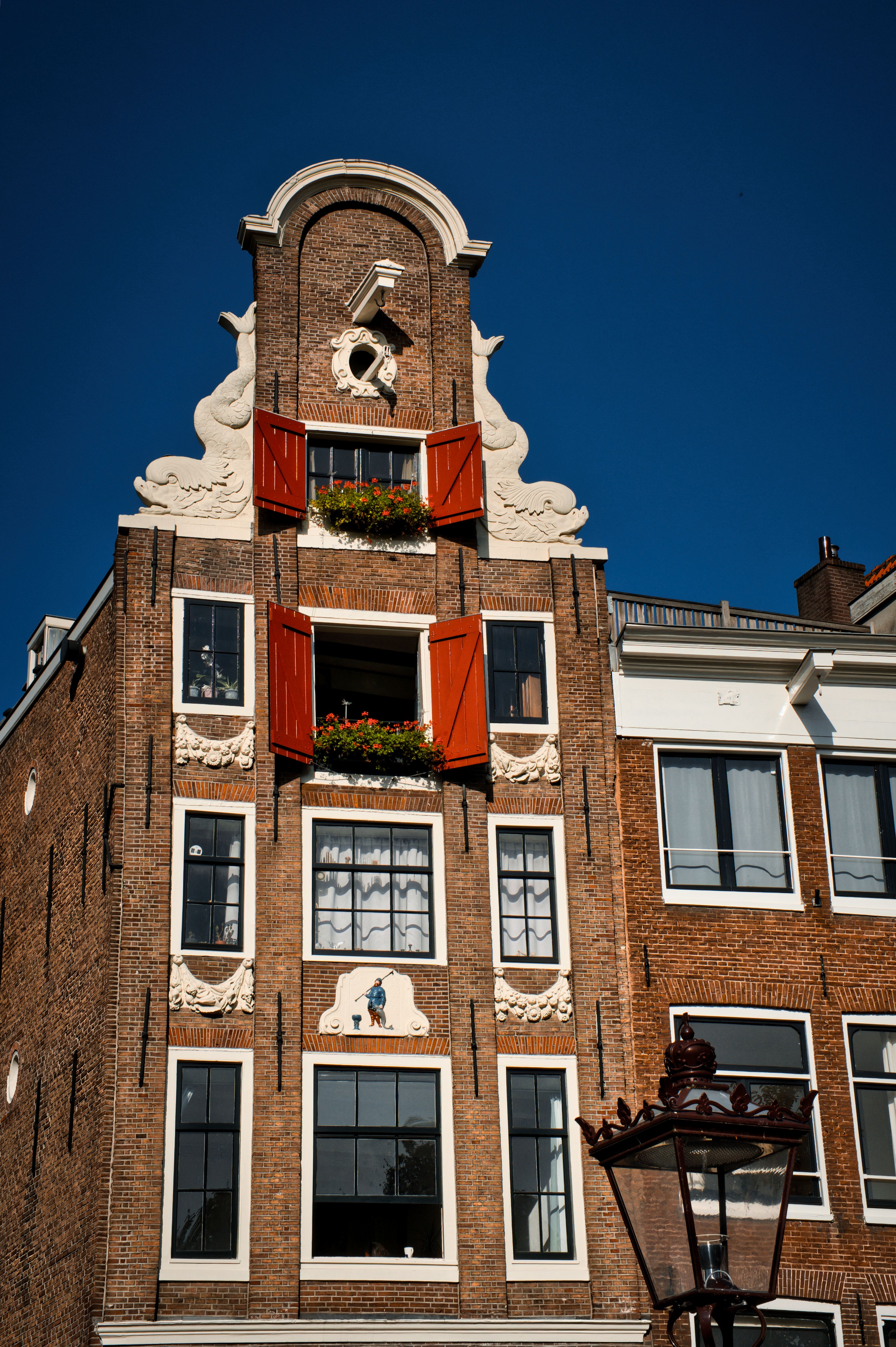 Historic canal house with red shutters in Amsterdam on a sunny day.