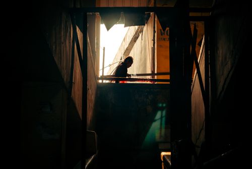 Free Silhouette of a person standing in a dimly lit stairwell, capturing dramatic lighting and shadows. Stock Photo
