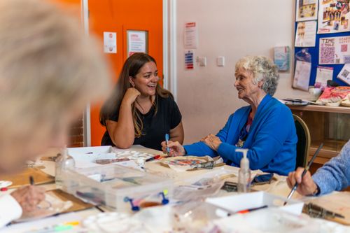 Free Adults and seniors engaging in a joyful art workshop, sharing creativity and laughter indoors. Stock Photo