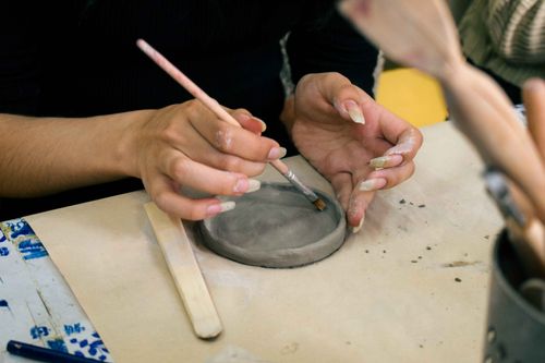 Free Close-up of a woman painting a ceramic dish by hand in a Valparaíso workshop, Chile. Stock Photo