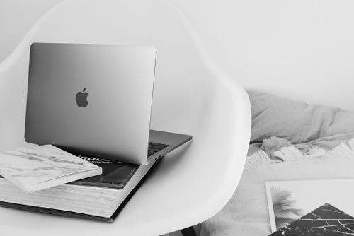 Free Modern portable netbook placed on book on white armchair near comfortable bed in light modern room at home Stock Photo