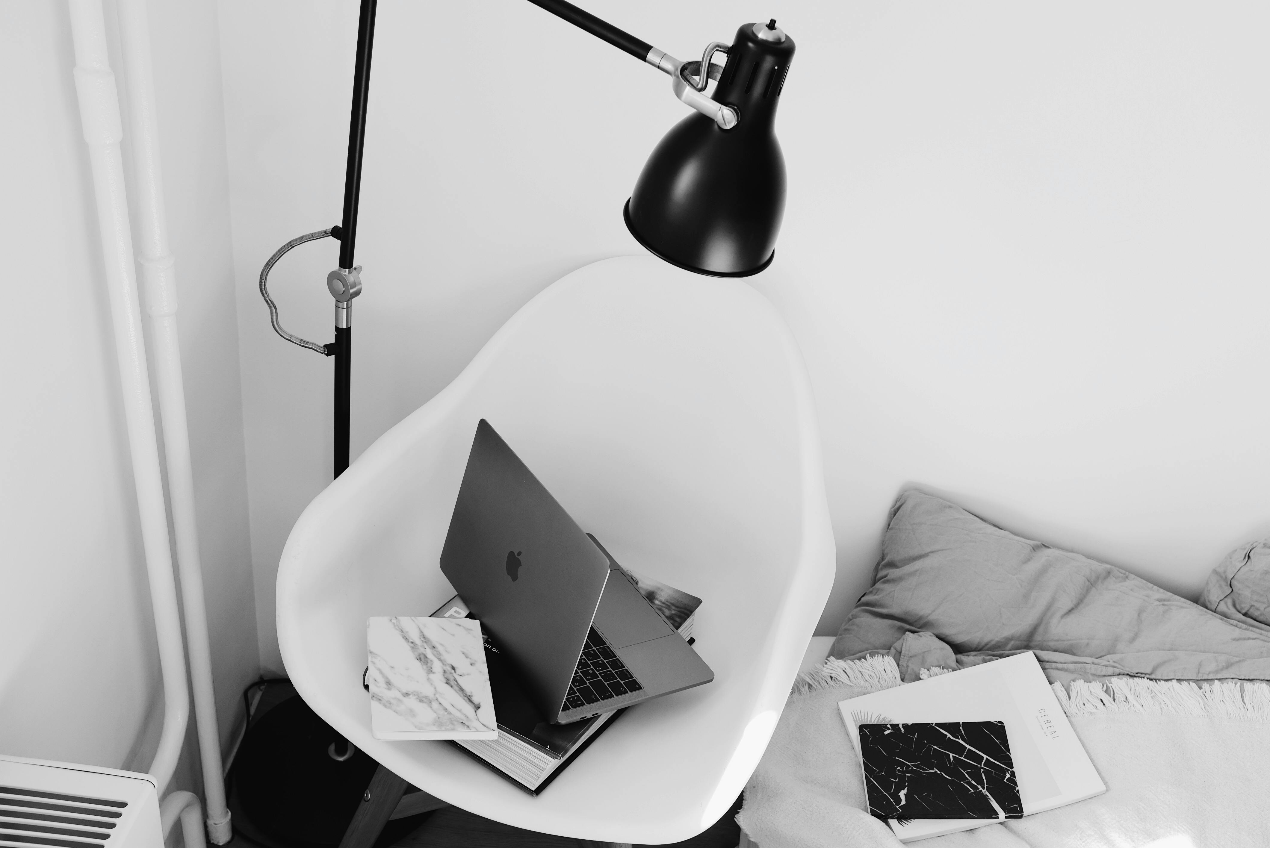 Stylish workplace with laptop and books on armchair under lamp in bedroom · Free Stock Photo