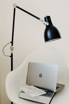 Stylish and modern home workspace featuring a laptop, chair, and lamp.