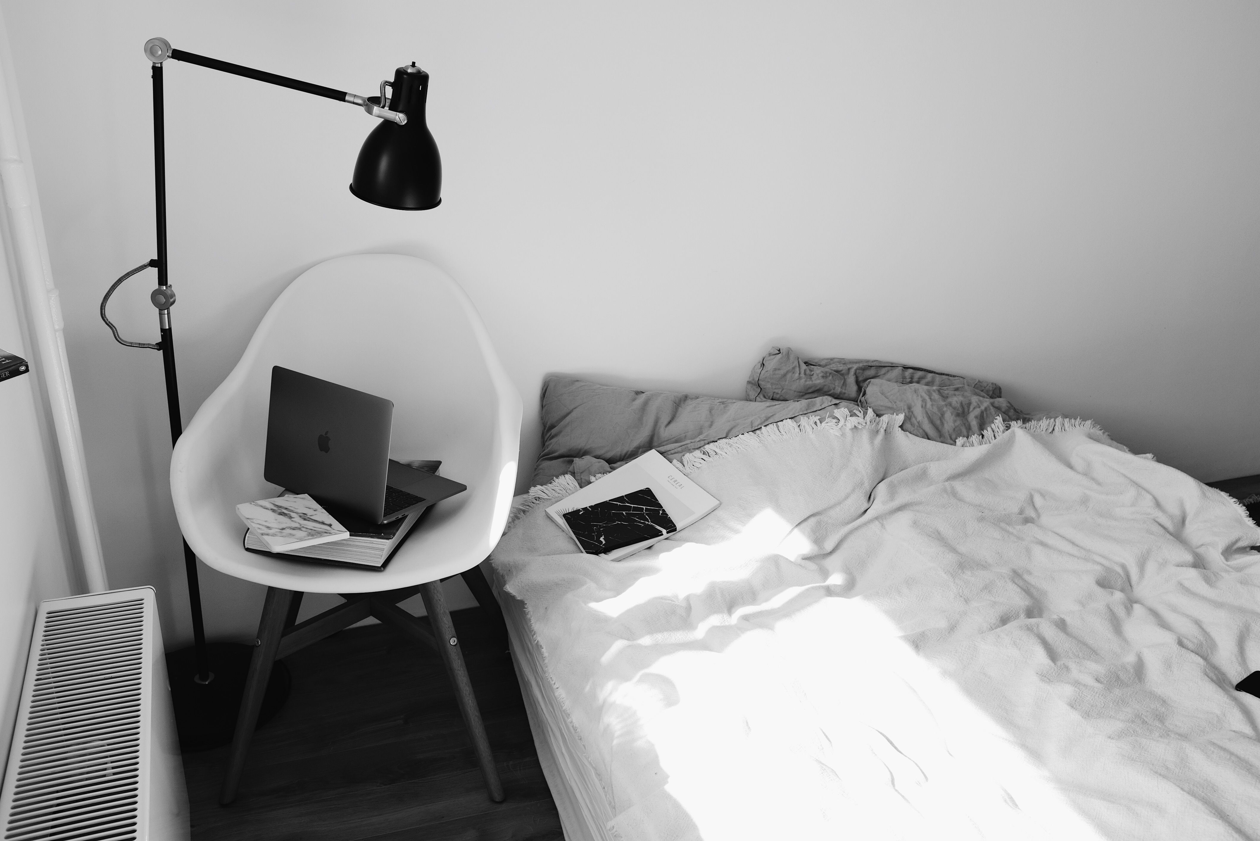 Calm bedroom corner with soft light and a simple chair beside a bed.
