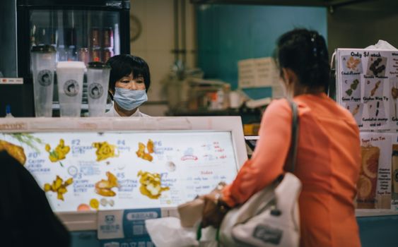 A woman wearing a mask orders at a food stall in Sydney. Social distancing observed.