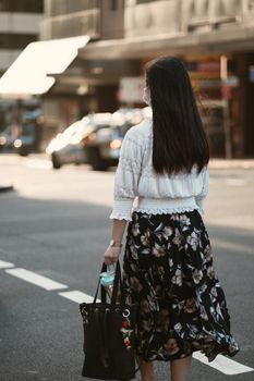 一位戴着面具的女士走在悉尼阳光明媚的街道上，展现了都市的时尚与安全感