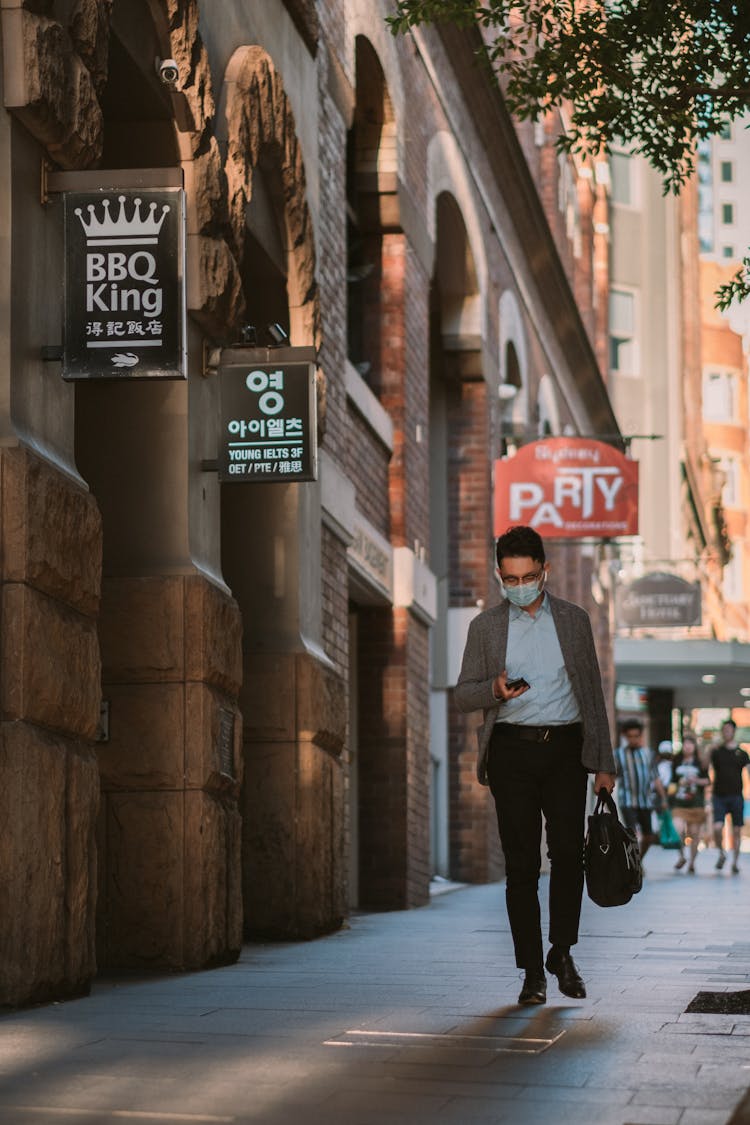 Man Texting While Walking On Sidewalk