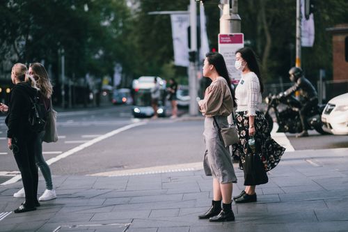 Free People wearing masks wait to cross the street in downtown Sydney, Australia during pandemic restrictions. Stock Photo
