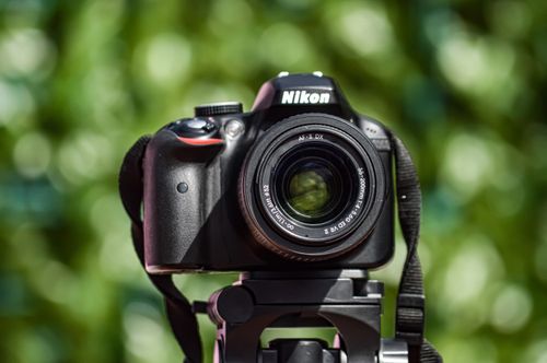 Free A DSLR camera mounted on a tripod captured against a blurred green background, perfect for photography-related themes. Stock Photo
