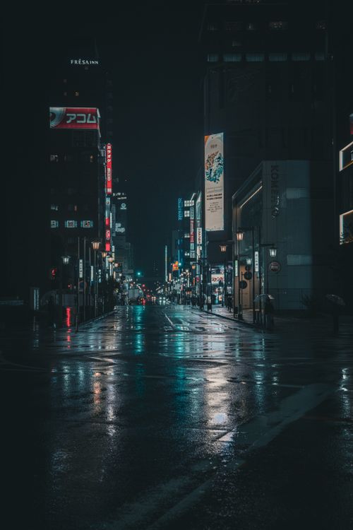Free Night view of a rainy street in Nagoya, Japan with neon lights reflecting on the wet pavement. Stock Photo