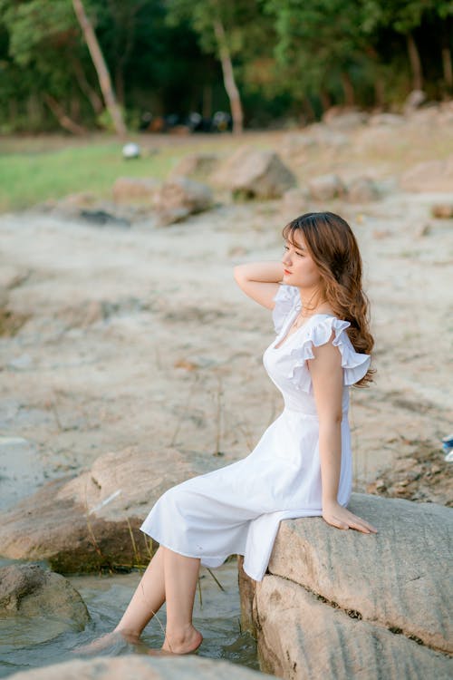Girl in White Dress Sitting on Rocks
