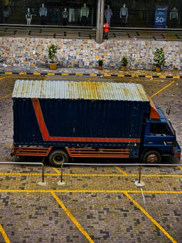 A vibrant delivery truck parked in an urban setting with mannequins and a storefront in the background.