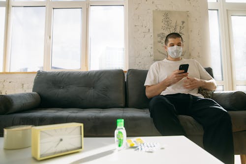 Free Man Sitting on Couch Holding His Smartphone Stock Photo