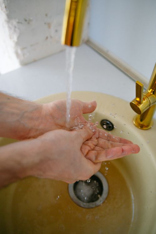 Free Hands under running water from a brass faucet, promoting hygiene and cleanliness. Stock Photo
