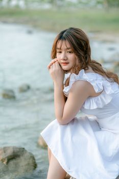 一位身着白色连衣裙的女子，静坐湖边，陷入沉思