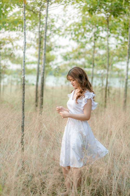 Woman in White Dress Standing on Brown Grass Field