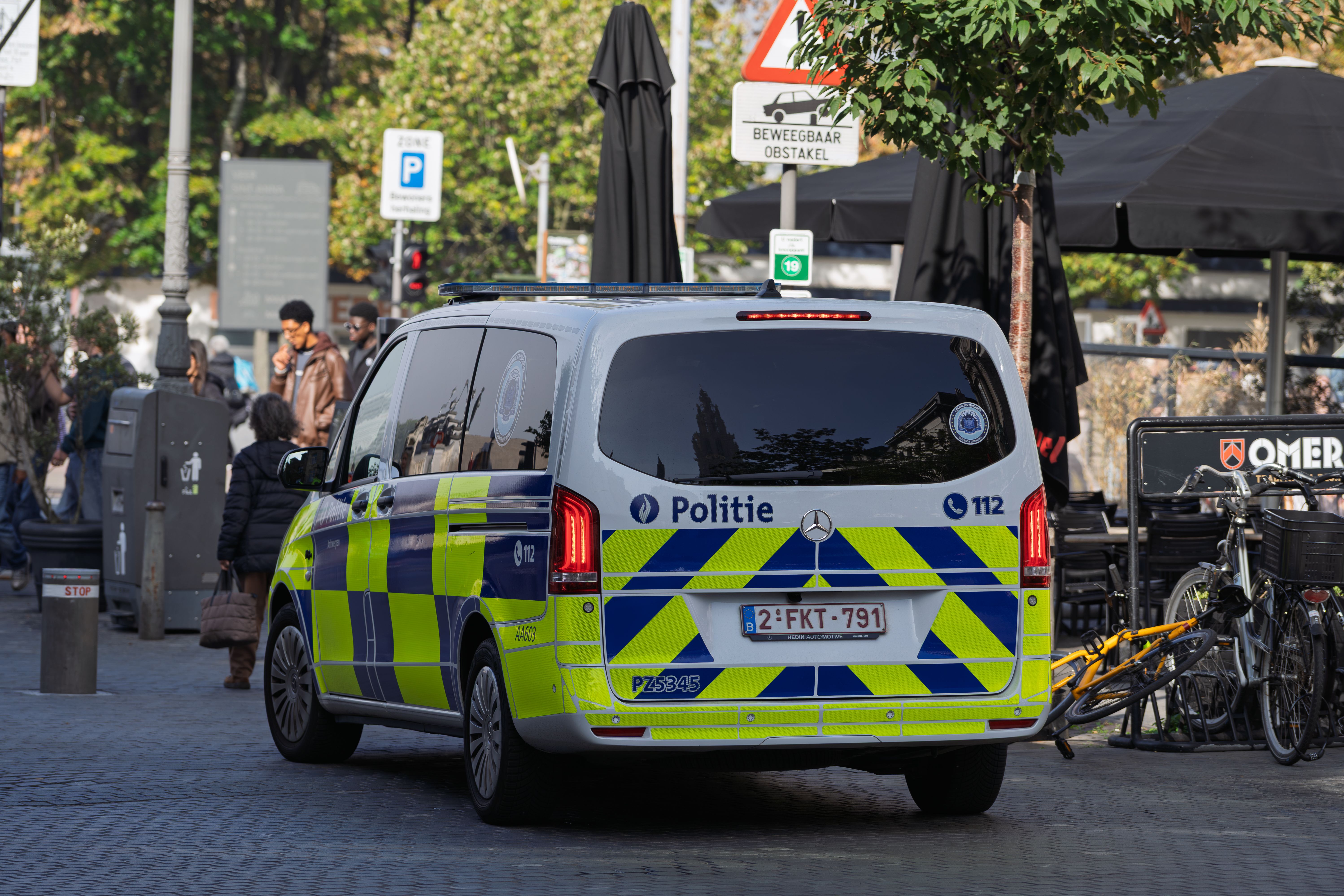 Police van parked on a European city street with pedestrians and bicycles nearby.