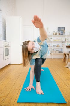 A woman wearing a face mask performs yoga at home, highlighting health during the pandemic.