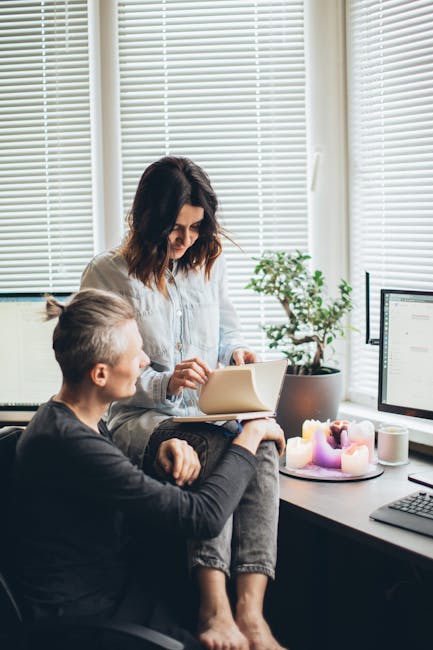 A couple smiling and working together in a home office setting with candles and natural light.