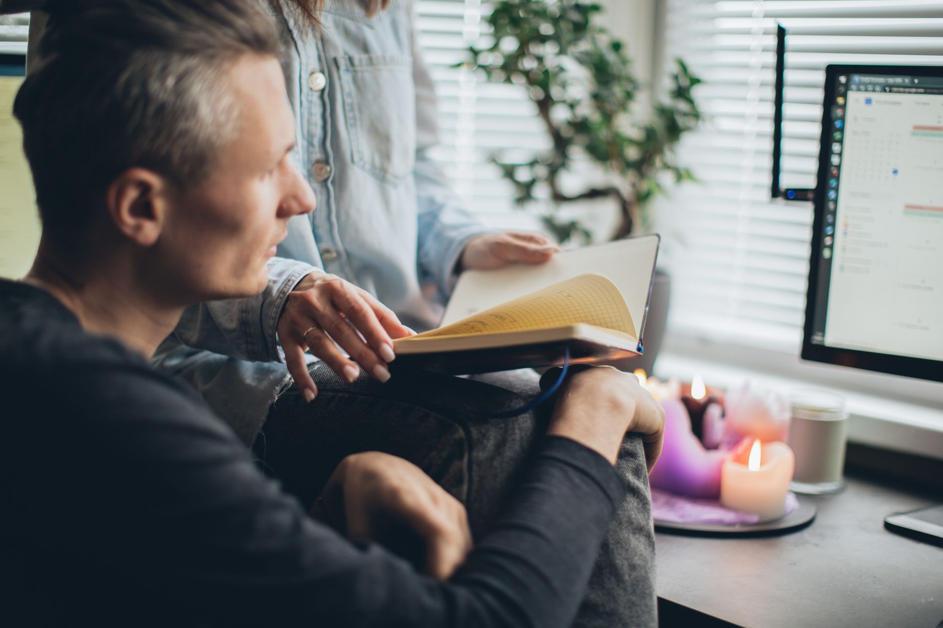 A couple enjoys remote work together, surrounded by warmth and technology in a cozy home office setting.