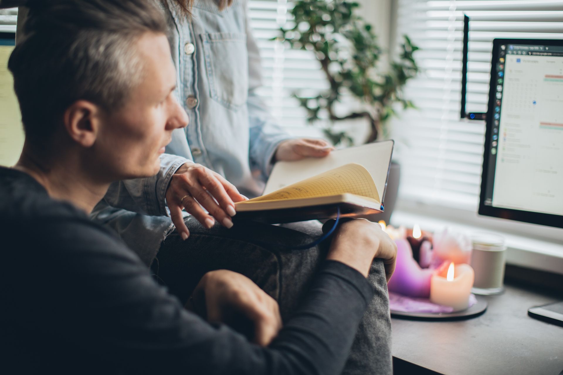 A couple enjoys remote work together, surrounded by warmth and technology in a cozy home office setting.