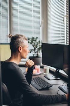 Person working remotely at a desk with a computer and candles, creating a cozy home office atmosphere.
