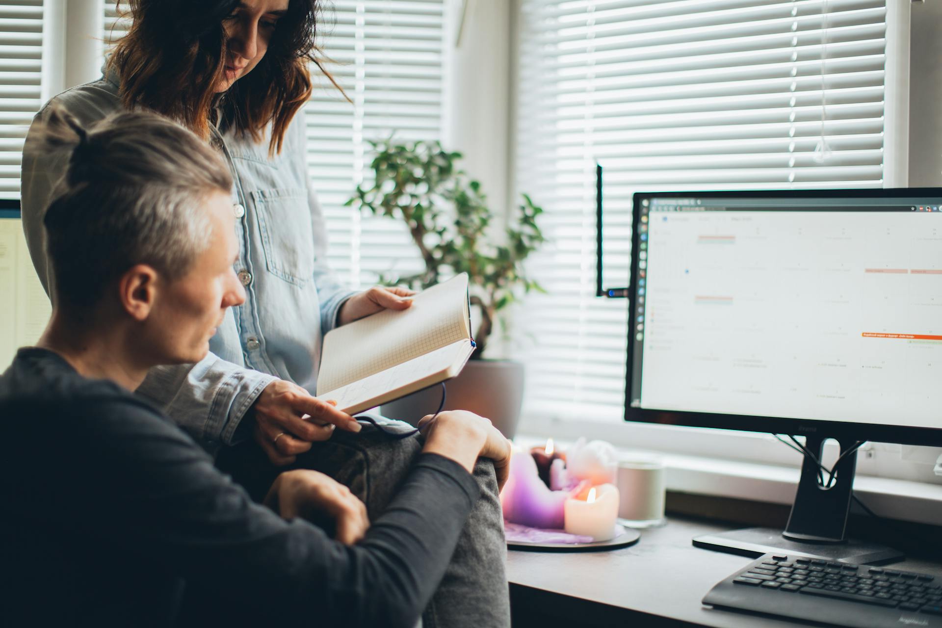 Couple working from home on a project, using a laptop and notebook in a cozy home office setting.