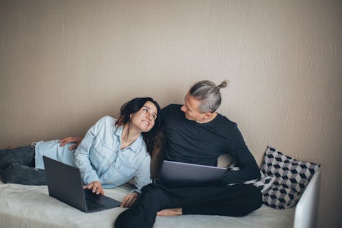 Couple Sitting on The Bed Working