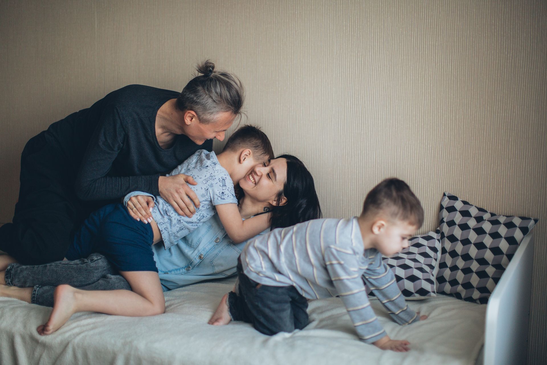 A warm and happy family moment with parents and children hugging and playing together on a bed.