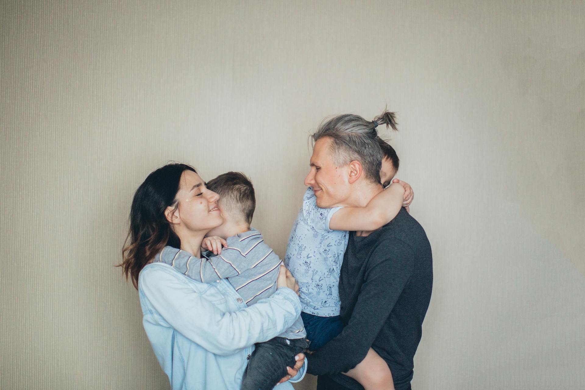 A heartfelt family moment with parents embracing their children indoors.