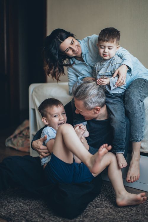 Free Joyful family of four playing affectionately together indoors, sharing a bonding moment. Stock Photo