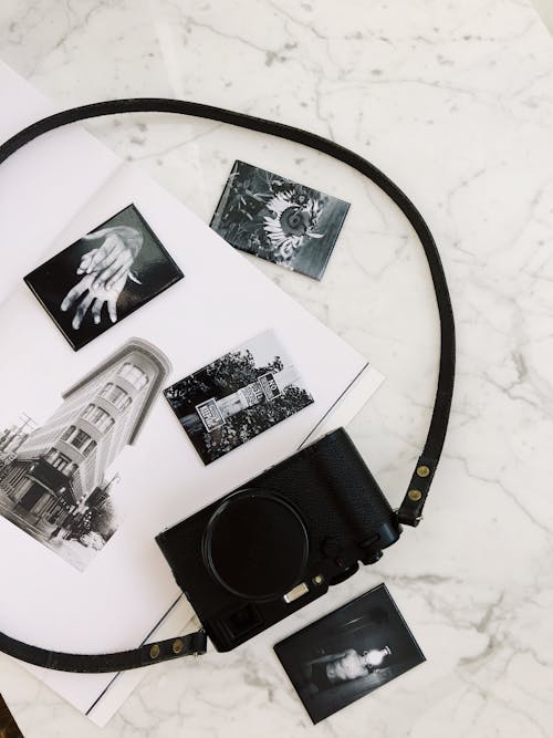 Photo camera placed on white marble surface on album