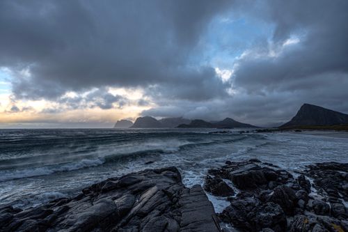 Free A dramatic seascape with dark clouds over rocky shores and crashing waves. Stock Photo