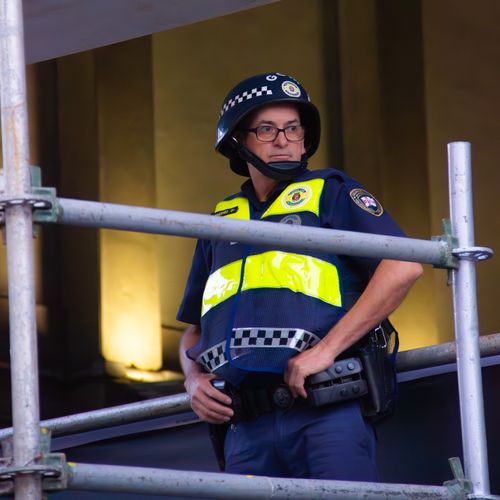 Free A vigilant security officer stands guard indoors with reflective vest and helmet, ensuring safety. Stock Photo