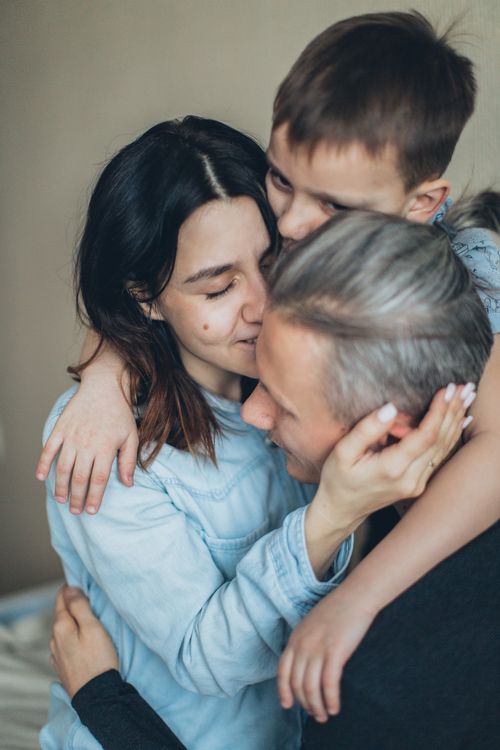 Free A heartfelt moment captured between a father, mother, and son sharing an affectionate embrace. Stock Photo