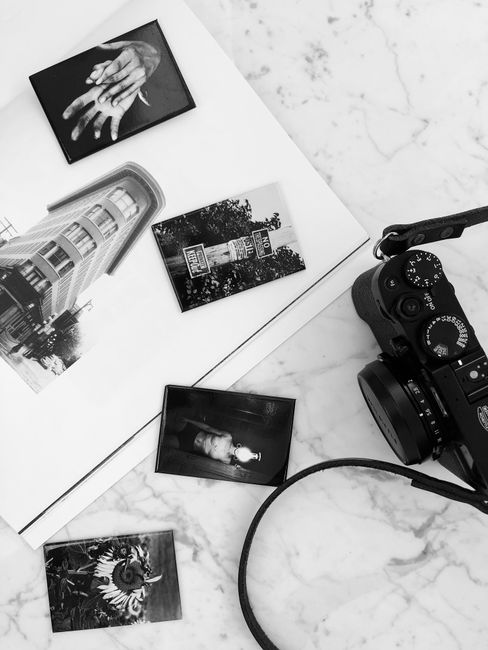 Black and white photo camera placed on white marble table near album with various pictures in modern studio