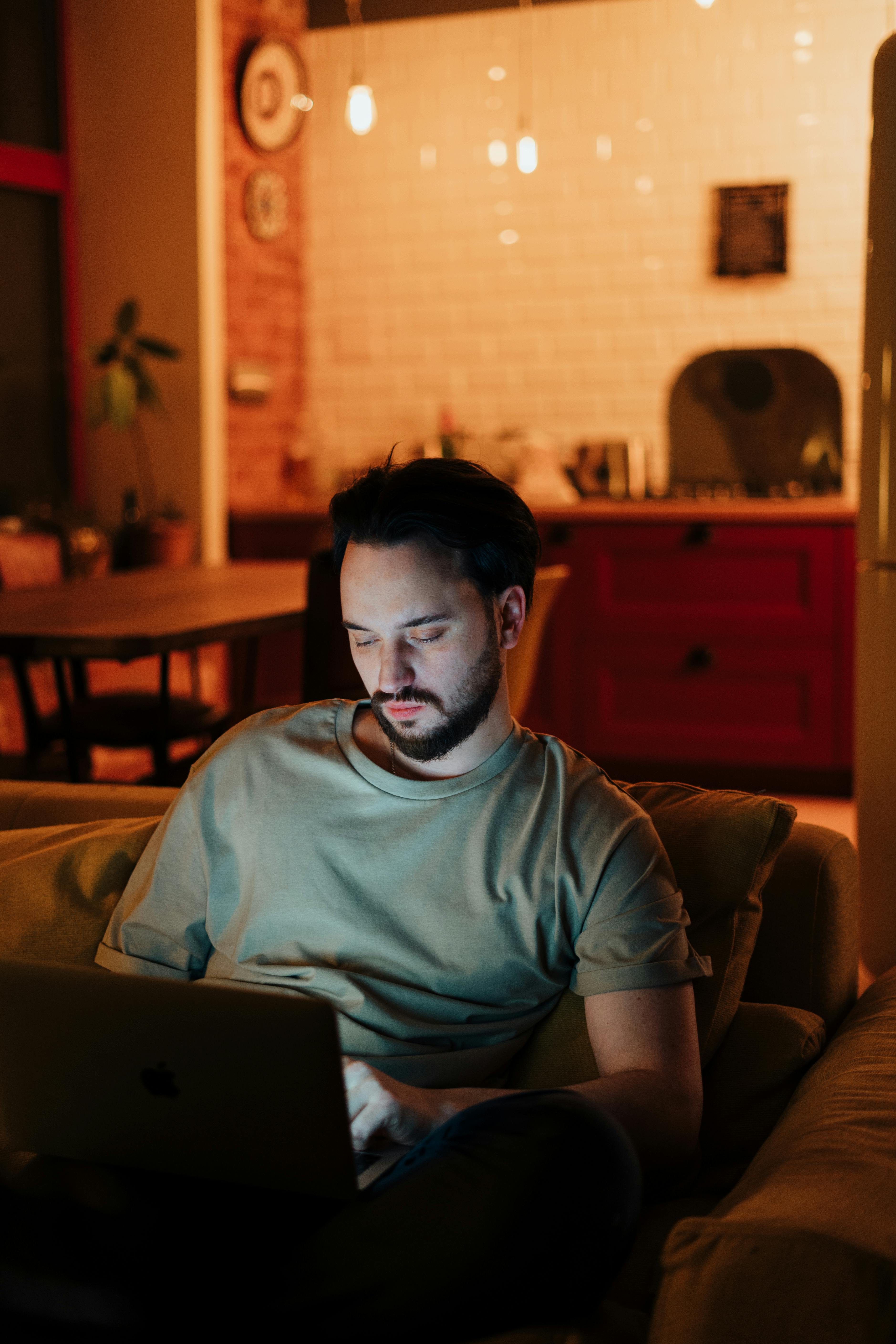 一名男子在温暖的灯光下，于舒适的家庭环境中使用笔记本电脑工作