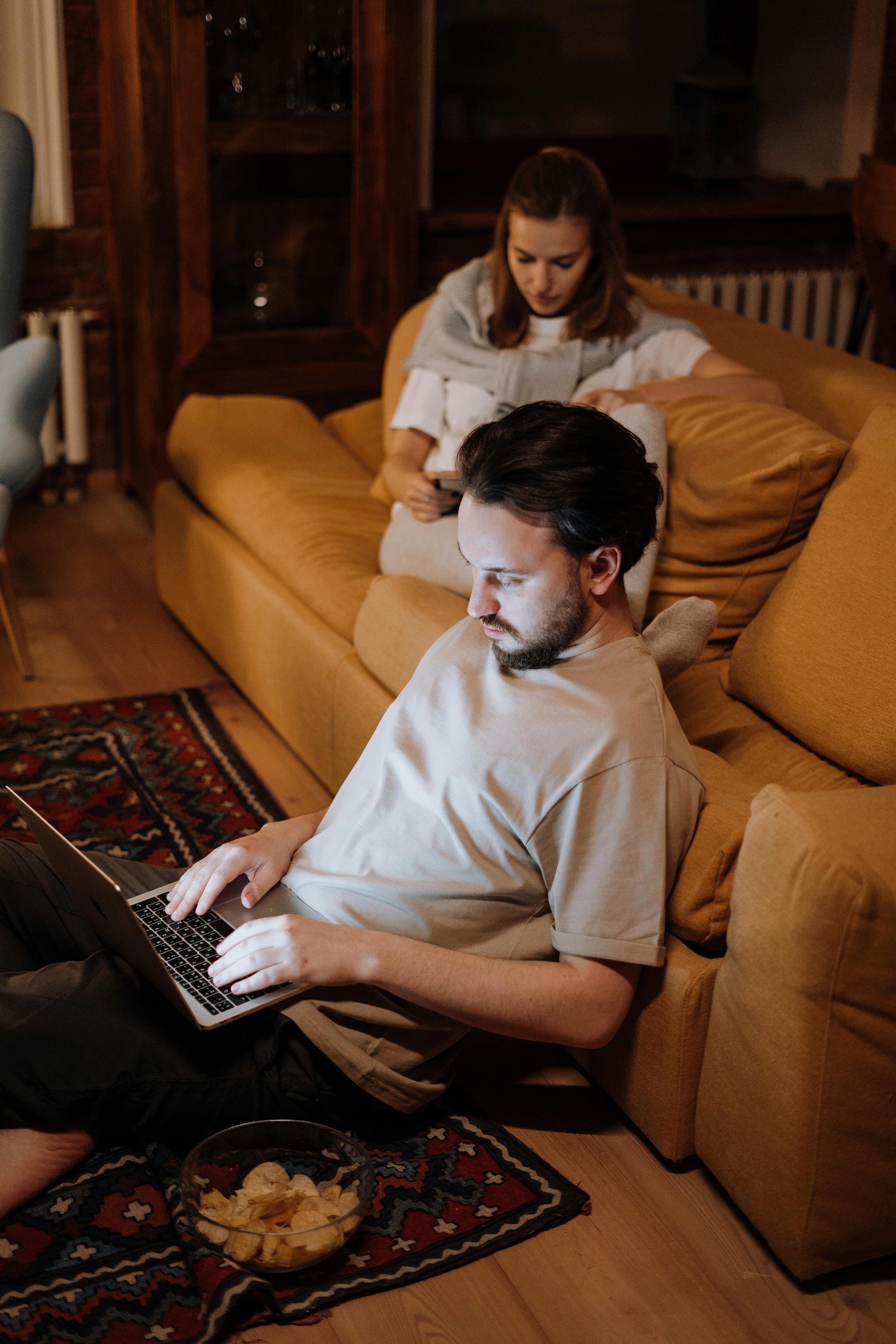 man in white crew neck t shirt sitting on brown sofa