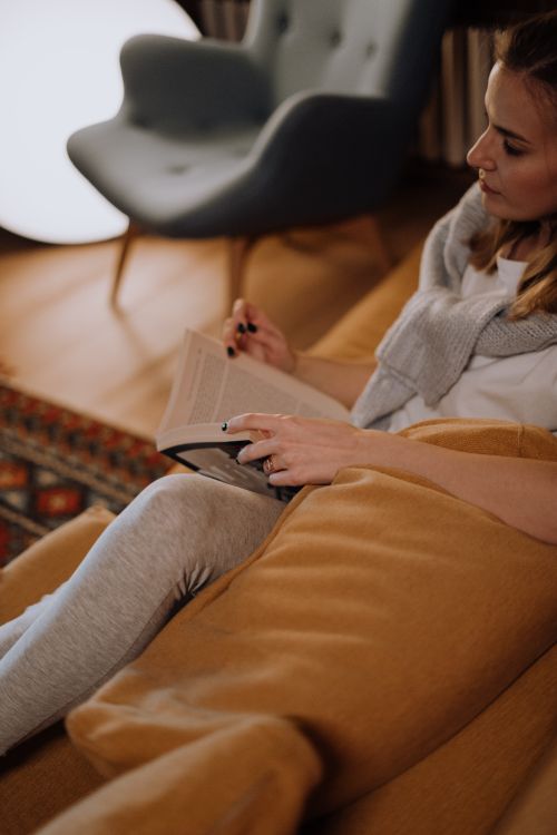 Free Woman enjoying a quiet evening reading in a warm, cozy living room. Stock Photo