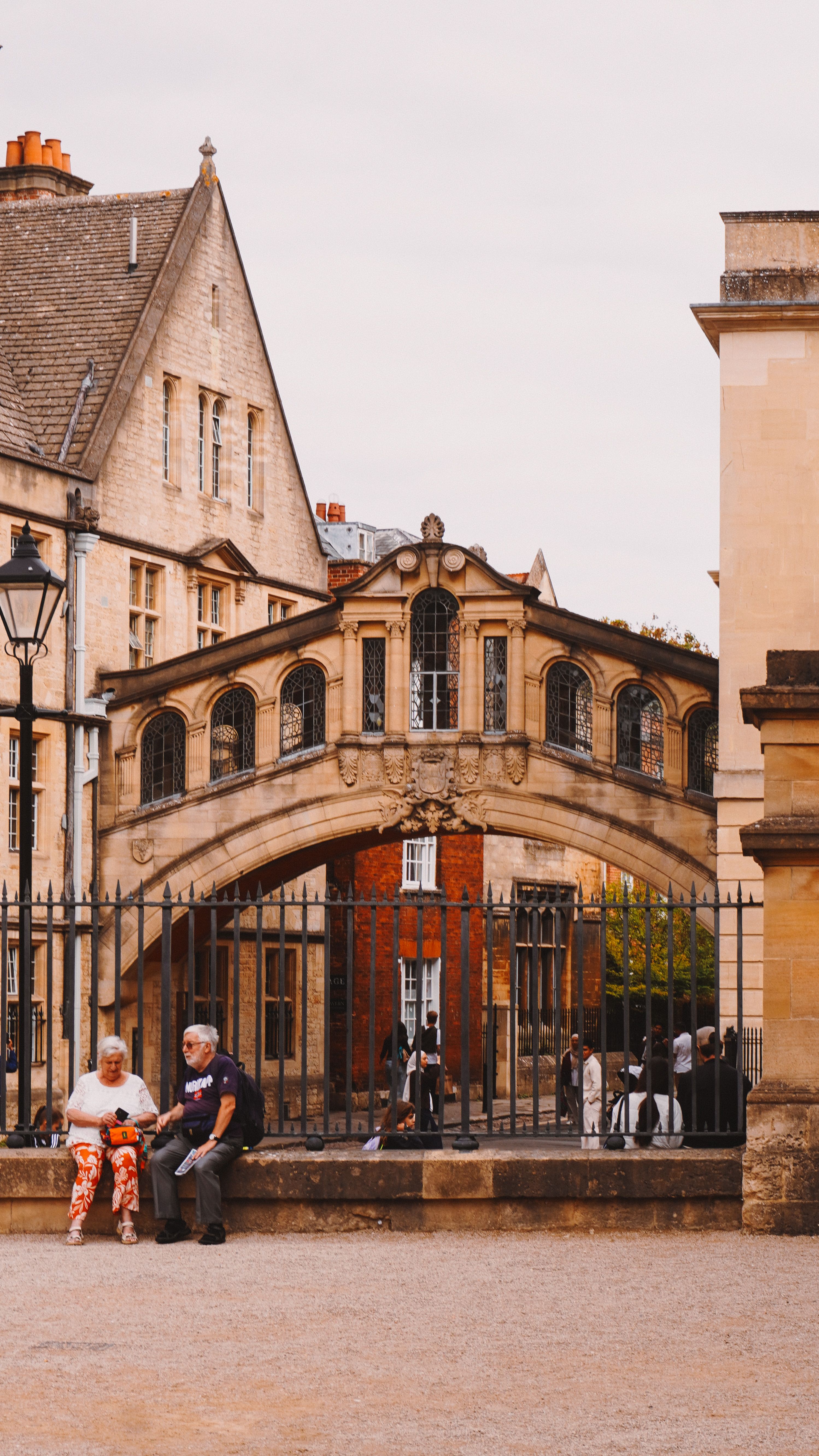 Charming view of the iconic Bridge of Sighs in Oxford with people relaxing nearby.